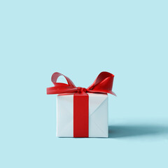 White gift box with red ribbon on pastel blue background. 3d rendering