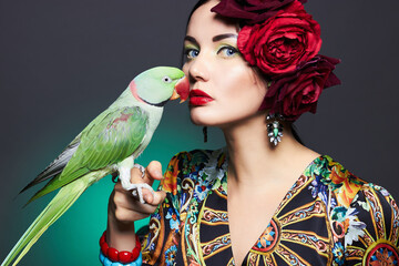 portrait of beautiful young woman with parrot and floral hat