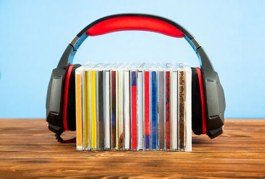 Headphones on a stack of CDs on a blue background.