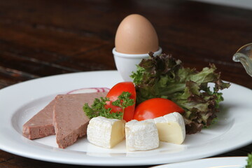 Breakfast with boiled egg, liver sausages, Brie cheese and garnish