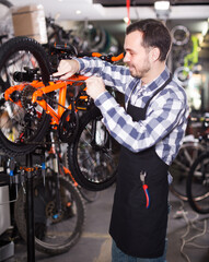 Fototapeta na wymiar Mechanic is working with bicycle's brakes in sports workshop.