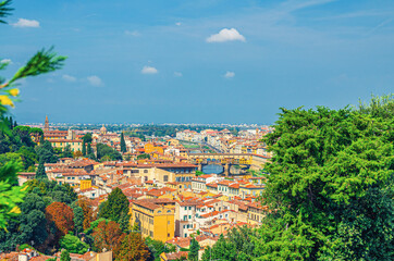 Fototapeta na wymiar Top aerial panoramic view of Florence city historical centre with Ponte Vecchio bridge over Arno river, buildings with orange red tiled roofs, palm trees, blue sky white clouds, Tuscany, Italy