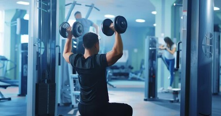 Active bodybuilder young asian man lifting heavy weights black dumbbells concentrating working out alone. Gym concept. Healthy lifestyle. - Powered by Adobe