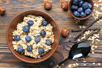 Bowl with tasty sweet oatmeal on wooden table
