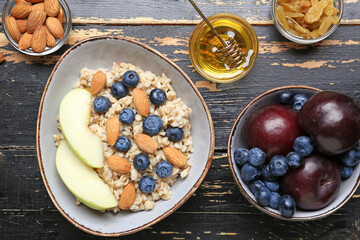 Bowl with tasty sweet oatmeal on wooden table
