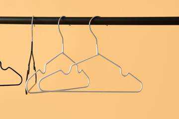 Rack with clothes hangers on color background