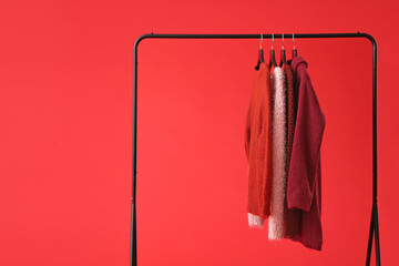 Rack with clothes on color background