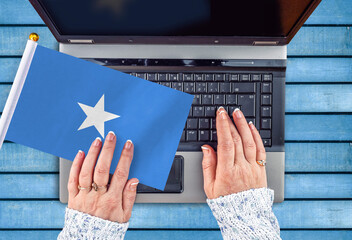 woman hands and flag of Somalia on computer, laptop keyboard 