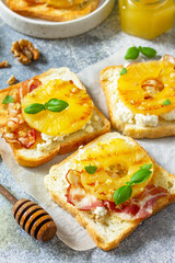 Healthy breakfast or snacks close-up. Toast with caramelized pineapple, bacon, nuts, and ricotta on a slate background.