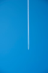 The white trail of the plane in the bright blue sky.