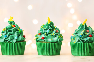 Tasty Christmas cupcakes on table