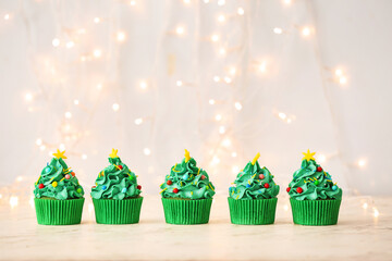 Tasty Christmas cupcakes on table