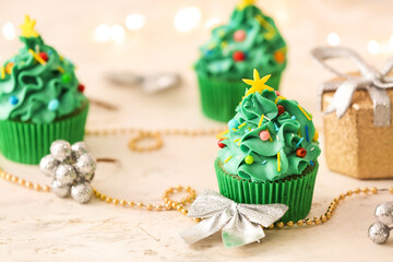 Tasty Christmas cupcakes and decor on table