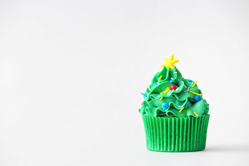 Tasty Christmas cupcake on light background