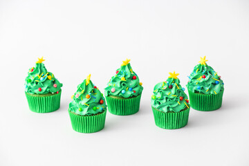 Tasty Christmas cupcakes on light background