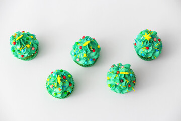 Tasty Christmas cupcakes on light background