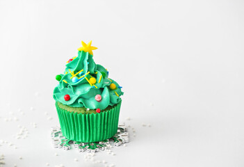 Tasty Christmas cupcake on light background