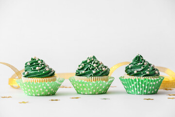 Tasty Christmas cupcakes on light background