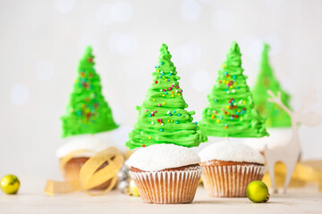 Tasty Christmas cupcakes and decor on table