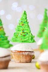 Tasty Christmas cupcakes and decor on table