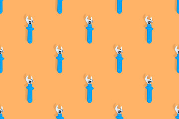 Wrench on an orange background. Seamless background from adjustable metal wrench. Seamless patterns.