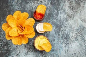 Overhead view of homemade crispy potato chips ketchup mayonnaise and sauce on gray background footage