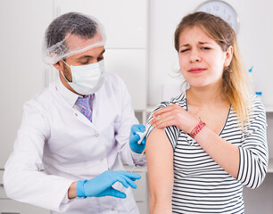 Young male doctor ready to make vaccination to teenage female visitor in hospital