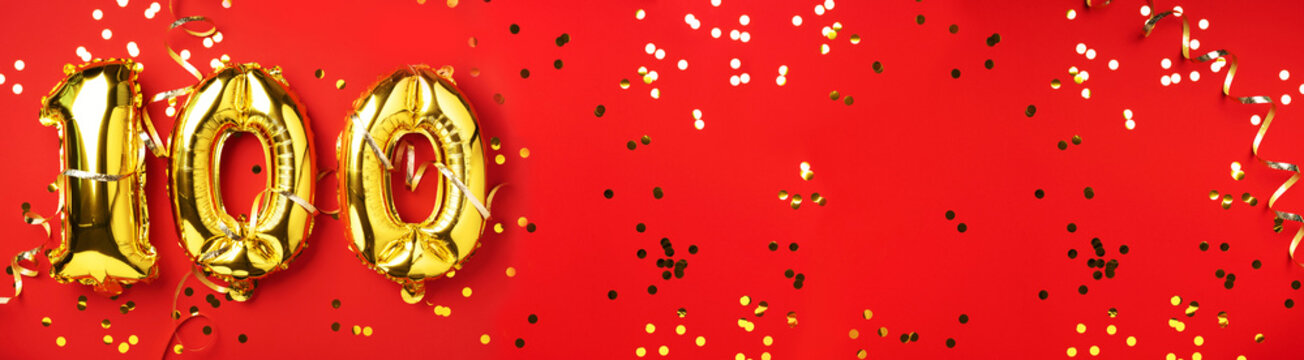 Gold foil balloon number, digit one hundred. Birthday greeting card with inscription 100. Anniversary celebration event. Banner. Golden numeral, red background. Numerical digit, light bokeh, glitter
