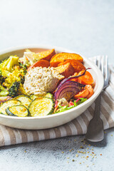 Baked vegetables with hummus bowl. Salad with baked sweet potato wedges, zucchini, broccoli and hummus. Vegan food concept.