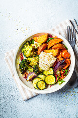 Baked vegetables with hummus bowl. Salad with baked sweet potato wedges, zucchini, broccoli and...
