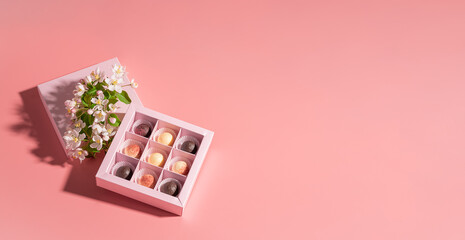 Chocolate candies in a festive box on a pink background. Holiday concept