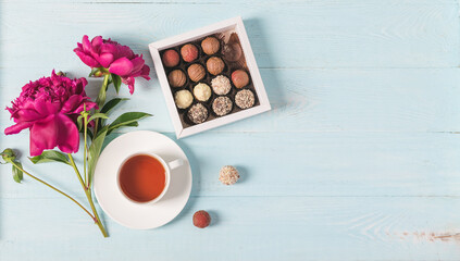 Cup of tea box of chocolates burgundy beautiful peonies blue gentle background