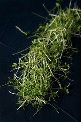 Heap of watercress microgreens on dark textured background