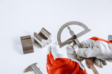 The worker measures the angle on the metal product with a protractor.