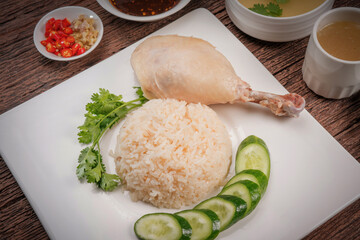 Hainanese chicken rice. Roasted Chicken Rice with soup, vegetable and Garlic, chili, ginger sauce on wooden back ground.