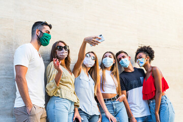 Selfie of young smiling people having fun together wearing face mask - Happy friends group taking selfie in park at european trip - Young people addicted by sharing stories on social network community