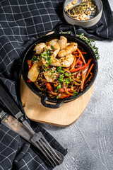 Udon stir fry noodles with chicken and vegetables in pan. Gray background. Top view