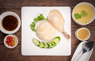 Hainanese chicken rice. Roasted Chicken Rice with soup, vegetable and Garlic, chili, ginger sauce on wooden back ground.