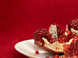 Pomegranate on a white plate on a red background