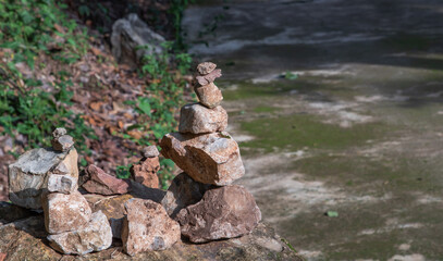 Balanced stone tower on walkway up the mountain with green plants in the background. Selective focus.