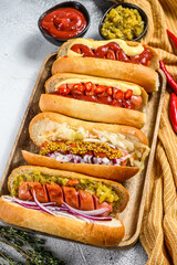 Hot dogs fully loaded with assorted toppings on a tray. Delicious hot-dogs with pork and beef sausages. White background. Top view