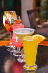Cocktails on the table. Different coloured drinks in different glasses on dark wooden table.
