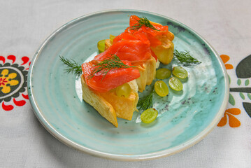 Traditional salmon puff pastry with fresh grapes. Delicious recipe. Served on a plate over traditional tablecloth.