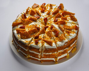 Closeup of a whole pumpkin layer cake with caramel and nut topping. Seasonal autumn cake with caramel syrup.