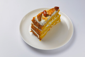 Closeup of one piece pumpkin layer cake with caramel and nut topping. Seasonal autumn cake with caramel syrup.