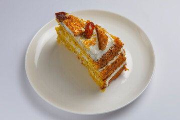 Closeup of one piece pumpkin layer cake with caramel and nut topping. Seasonal autumn cake with caramel syrup.
