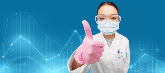 medicine, profession and healthcare concept - asian female doctor or scientist wearing face protective medical mask, gloves and goggles showing thumbs up over virtual diagram charts on blue background