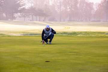 Close-up of a golf player on course aiming for put shot during a tournament