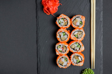 Different Sushi rolls, sushi set rolled in cheese. California philadelphia sushi rolls served on a black chalk board.