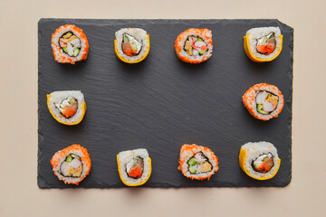 Different Sushi rolls, sushi set rolled in cheese. California philadelphia sushi rolls served on a black chalk board.